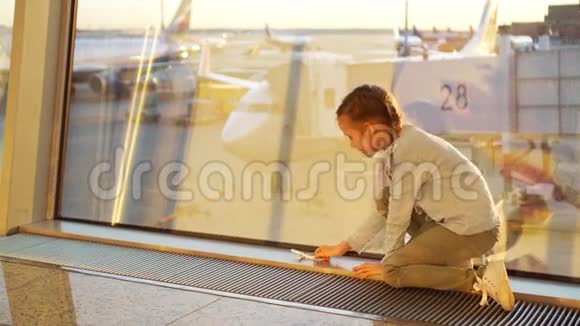 可爱的小女孩在机场玩小模型飞机等待登机视频的预览图