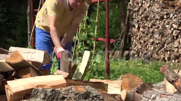 农夫在柴房附近的乡下用斧头劈开坚硬的木头4K视频的预览图