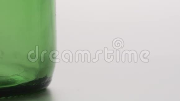 黄色镜头瓶盖在绿色瓶子附近掉落的宏观镜头视频的预览图