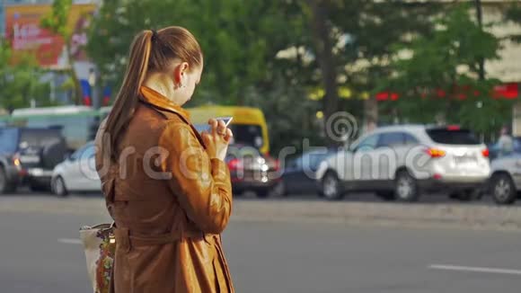 美丽的年轻女孩站在城市交通的背景下中等镜头视频的预览图
