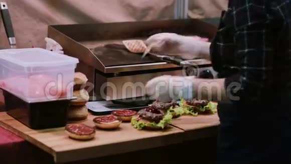 一个白手套的厨师做汉堡男人把汉堡和肉串放在最上面把每个汉堡都穿在后视图上视频的预览图