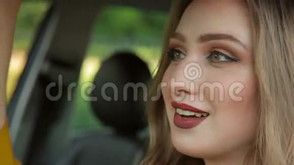 坐在车里的漂亮女孩可爱的金发女人在车里涂口红视频的预览图
