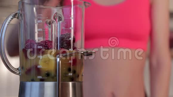 快乐健康的女性把水果放进搅拌机里准备奶昔视频的预览图