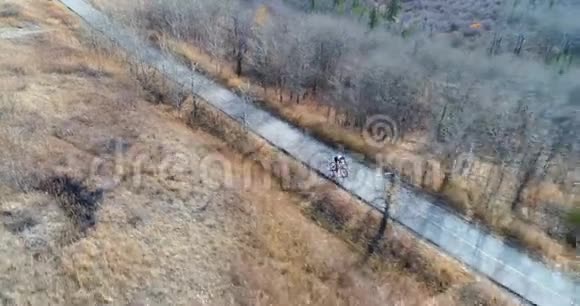 骑自行车的人在森林中的乡村公路上骑自行车视频的预览图