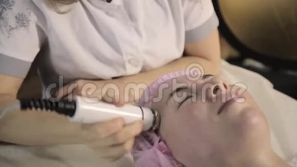 美丽的女人闭着眼睛把射频举在她的脸上在没有手术的情况下改善外观视频的预览图