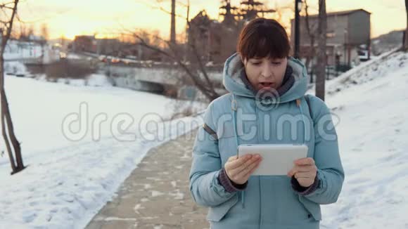 冬天一位年轻女子在户外使用数码平板电脑视频的预览图