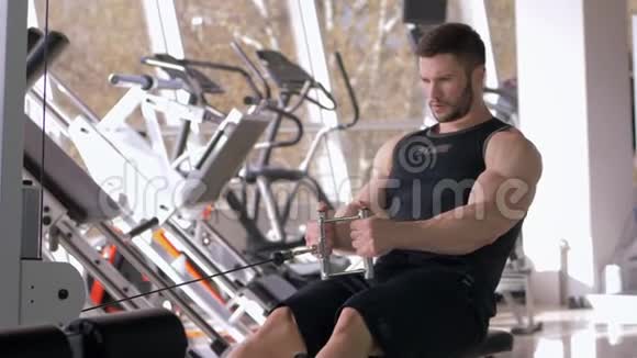 在健身俱乐部锻炼身体的职业运动员在牵引模拟器上进行肌肉锻炼视频的预览图