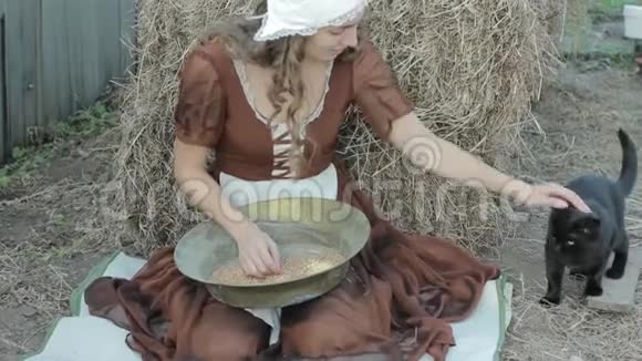 一个穿着乡村服装的漂亮女人坐在干草上把谷物切碎视频的预览图