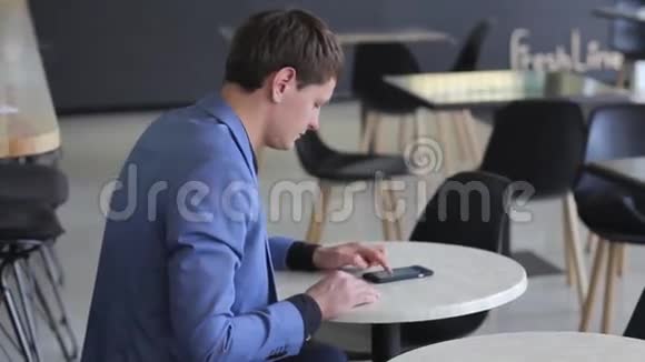 一个年轻人在咖啡馆里用他的移动设备视频的预览图