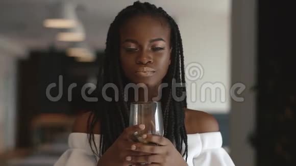 年轻漂亮的非裔美国女时装模特手里拿着酒杯假装喝着视频的预览图