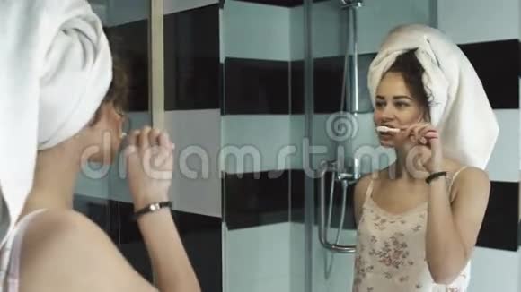 漂亮的女孩在浴室里用毛巾在头上刷牙镜子里的倒影的概念视频的预览图