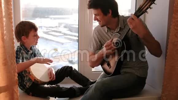 演奏乐器爸爸在弹吉他儿子在坐在窗台上打鼓视频的预览图