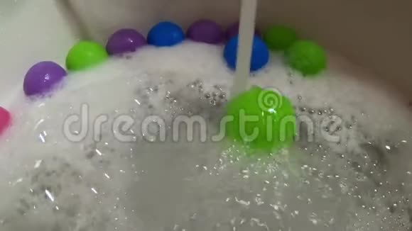 浴缸里的水流滚动着绿色塑料球视频的预览图