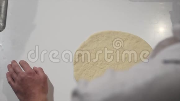 厨师在披萨店用金属瓢在披萨面团上撒番茄酱视频的预览图