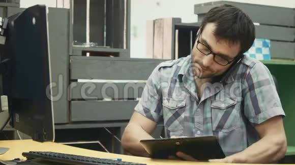 一个戴眼镜的忙碌的成年男人在手机上聊天在键盘上打字视频的预览图