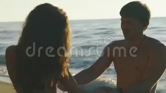 快乐的年轻夫妇在沙滩上玩冲浪英俊的男人和漂亮的姑娘手牵手视频的预览图