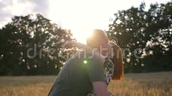 夕阳下一对年轻夫妇在田野上的慢镜头男人旋转的女人视频的预览图