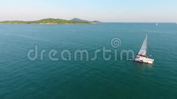 卡特玛兰帆船在蔚蓝的海水中航行天堂岛在地平线上高清空中镜头泰国普吉岛视频的预览图