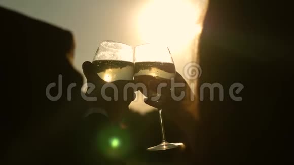 香槟在阳光下闪耀和泡沫情侣们在夕阳的映衬下捧着酒杯和起泡葡萄酒视频的预览图