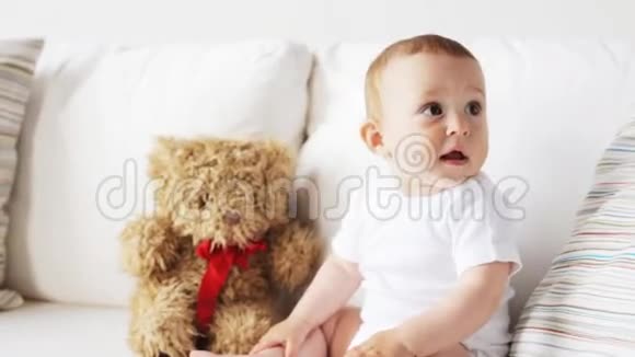 5带着玩具熊的宝宝坐在家里的沙发上视频的预览图
