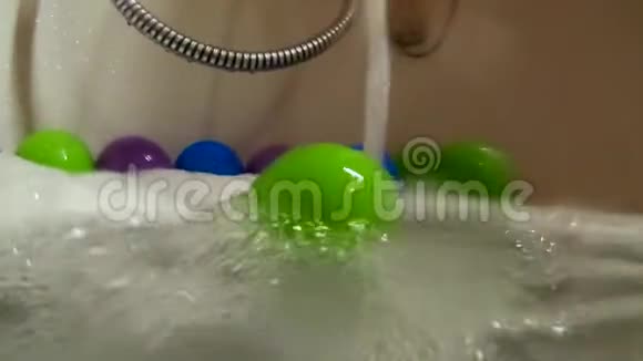 浴缸中的绿色塑料球在水流中滚动动作缓慢视频的预览图