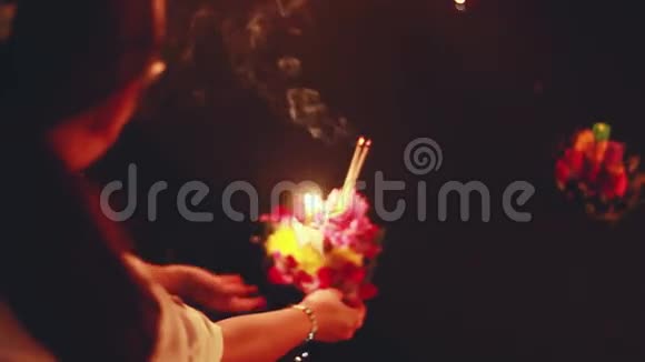 在泰国庆祝LoyKratong节双手捧起池塘里的鲜花和蜡烛视频的预览图
