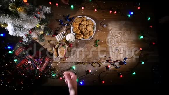 木制棕色桌子上面装饰着圣诞用品和花环手从盘子里拿饼干视频的预览图