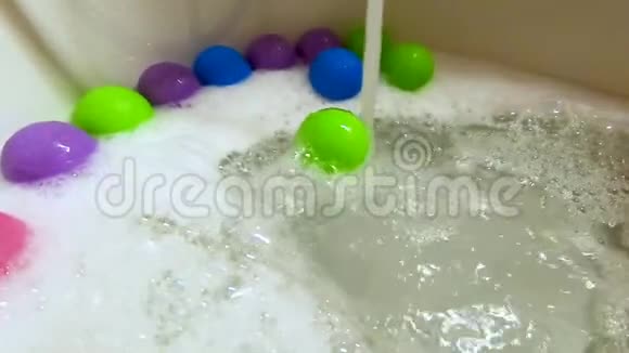 浴缸中的绿色塑料球在水流中滚动动作缓慢视频的预览图