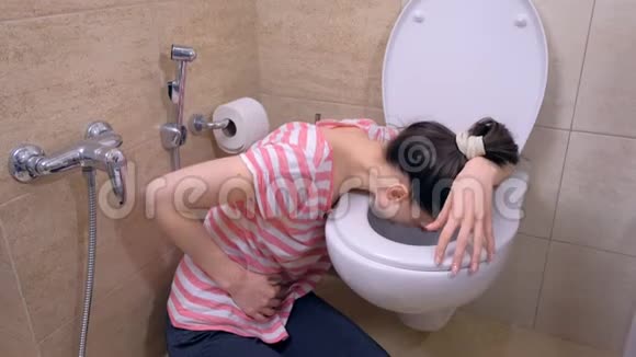 年轻的患病妇女胃疼坐在家里的地板上呕吐流感症状视频的预览图