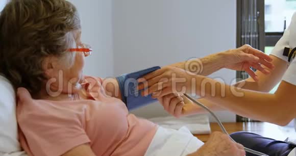 医生在4k床上检查老年妇女的血压视频的预览图