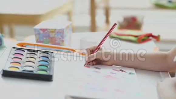 幼儿手中的彩色红色铅笔在桌子上画画视频的预览图
