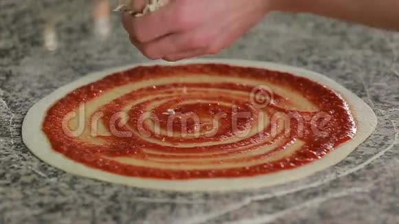 在已经涂上番茄酱的披萨面团上加入奶酪视频的预览图