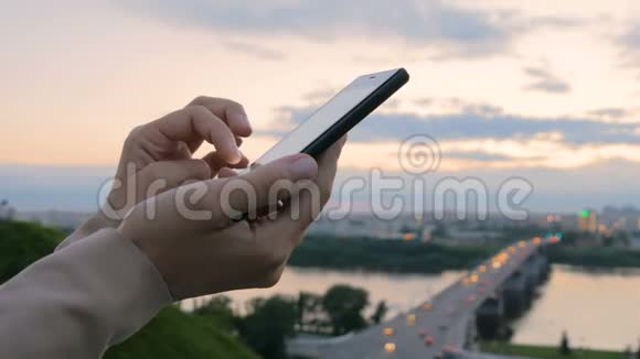 日落后城市里使用智能手机的女人视频的预览图