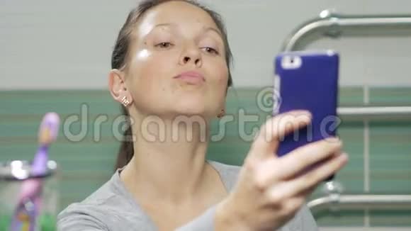 年轻迷人的女人在酒店房间的浴室里做自拍手机她微笑着改变姿势视频的预览图