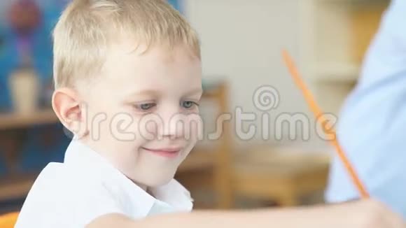 一个金发可爱男孩的肖像男孩用油漆画画视频的预览图
