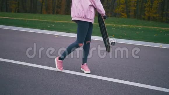 年轻漂亮的金发时髦女子在路上慢吞吞地走着滑板长板视频的预览图
