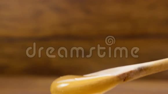 用木制背景从勺子中倒入金色蜂蜜2号视频的预览图