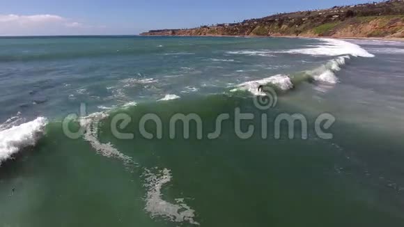 在阳光明媚的夏日海景海岸乘坐巨大的白色海浪冲浪4k空中视频的预览图