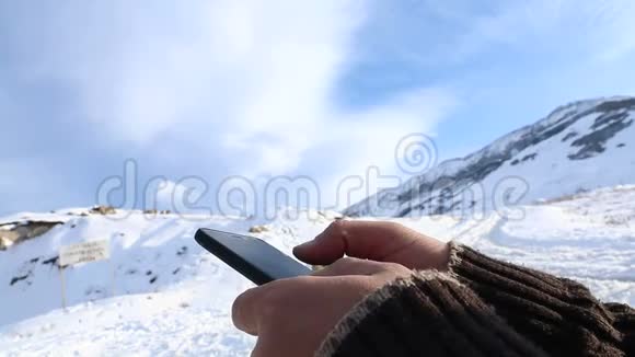 在山顶的智能手机上搜索东西的人用手拿手机视频的预览图