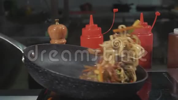 厨师薯条面条各种蔬菜和肉在热炒锅上视频的预览图