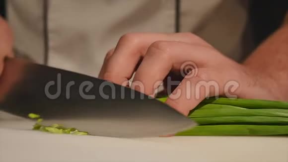在木板上用刀切洋葱在框架内不用手切割绿色厨师切食材视频的预览图