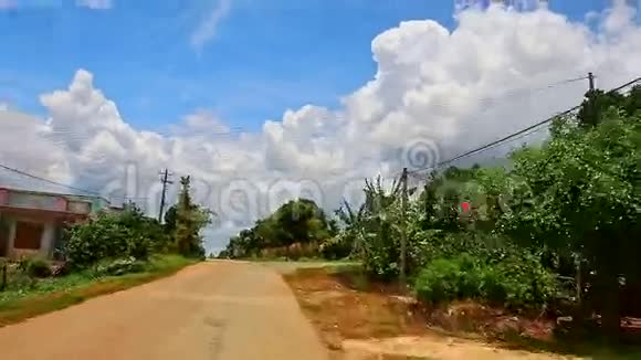 沿着公路穿过村庄经过房屋棕榈树对天空视频的预览图