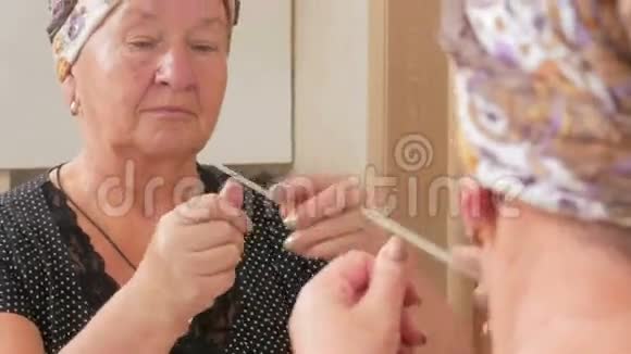 年老的女人在洗澡时自己修指甲它使用钉子文件它可以在镜盒里看到反射美容视频的预览图