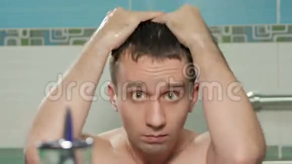 年轻有魅力的男人在酒店房间的浴室里洗过澡后就会挺直发型他双手梳着头发视频的预览图
