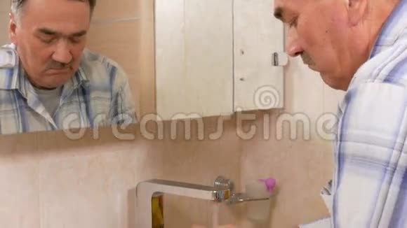 老人在洗澡时用肥皂洗手治疗后他用水冲洗双手纯洁的概念视频的预览图