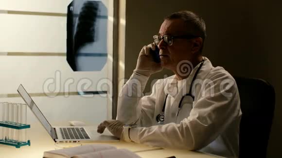 穿着听诊器的老医疗顾问用手机和笔记本电脑提供建议视频的预览图