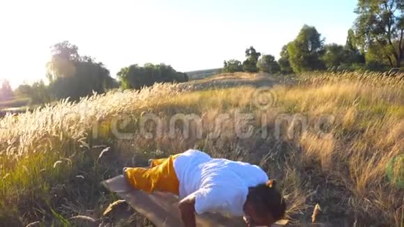 在阳光明媚的日子里运动男子在草地上练习瑜伽年轻人在球场上做运动美丽美丽视频的预览图