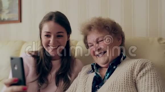 美丽的祖母和女儿正在家里坐在沙发上自拍和微笑视频的预览图