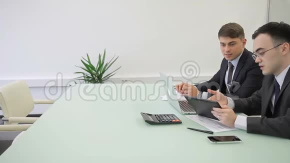 年轻人在现代办公室工作使用笔记本电脑和平板电脑视频的预览图