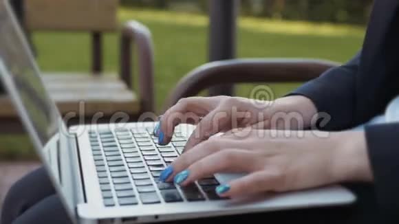女子手在笔记本电脑键盘女子打字笔记本户外特写视频的预览图